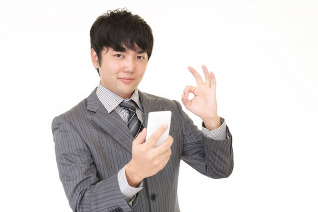 スマホを持ちokサインをするビジネスマン