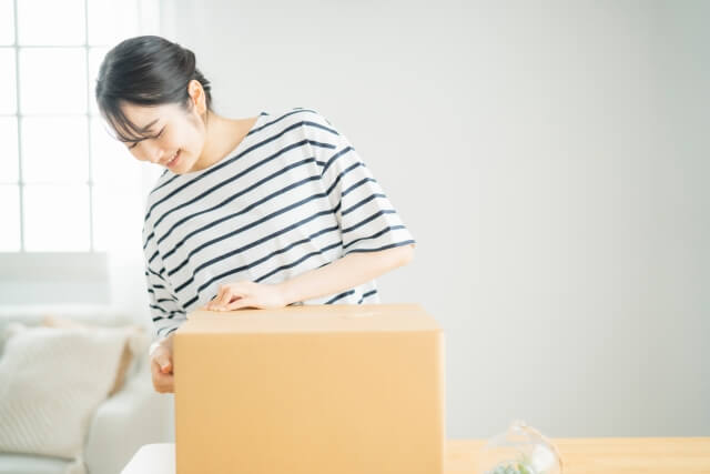 ダンボールの蓋をしめようとする女性