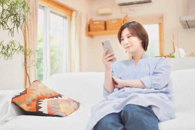 スマホをソファに座ってみている女性