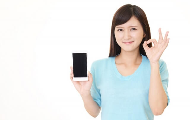 スマホを持ちokサインをする女性