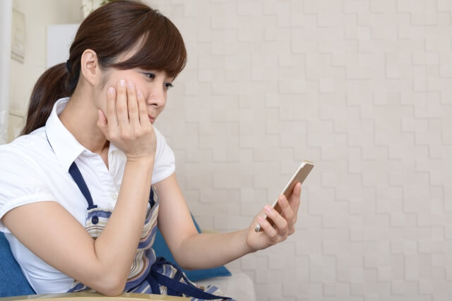 スマホを見て悩む女性