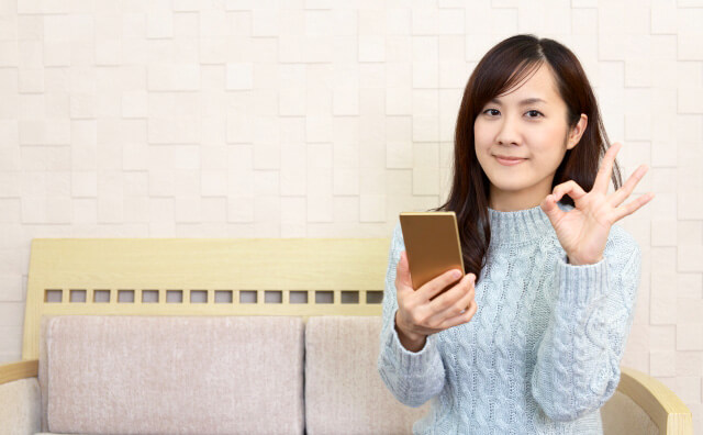 スマホをもってOKサインする女性