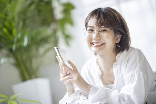 スマホをもって笑顔になっている女性