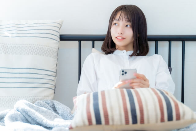 スマホをベッドで扱う女性