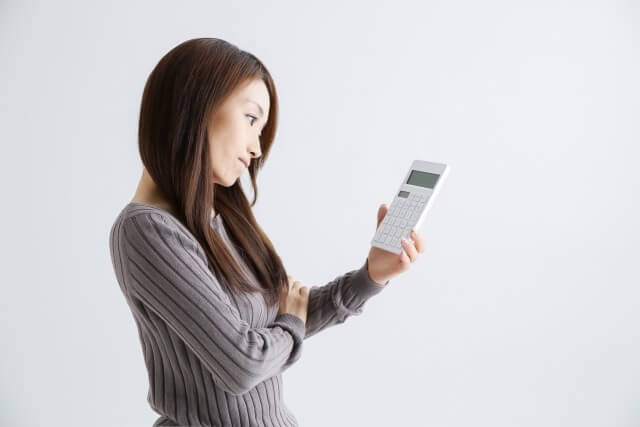 電卓を持ち考える女性