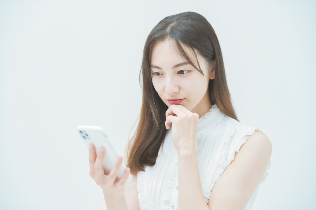 スマホを見て何か不安そうな女性