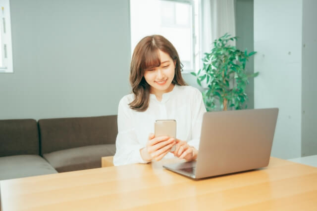 パソコンとスマホを使っている女性