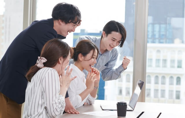 会社でパソコンを見て喜ぶ人々
