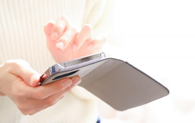 女性が手帳型ケースのスマホを持っている