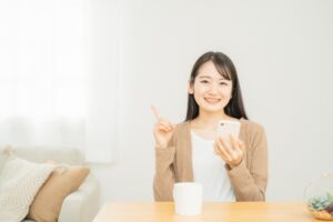 スマホをもち指さす女性