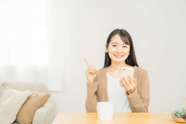 スマホをもち指さす女性