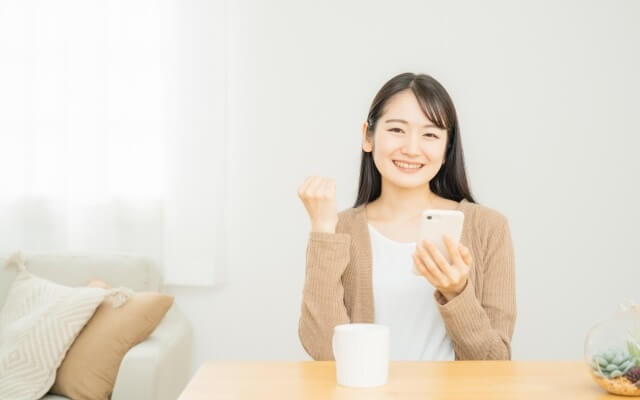 女性がスマホを持ち喜ぶ様子
