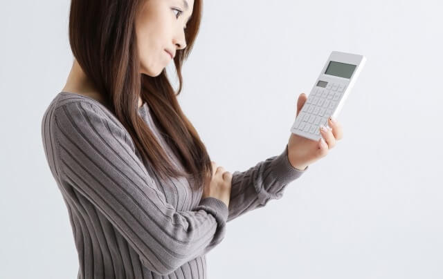 電卓を持って考えている女性