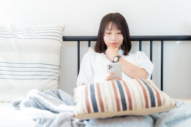 ベッドでスマホを見る女性