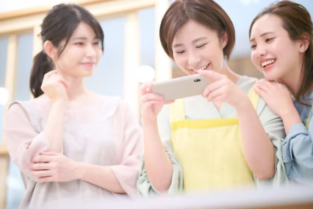 スマホで料理を撮影する女性とその友達