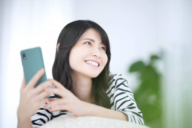 スマホをもって微笑む女性