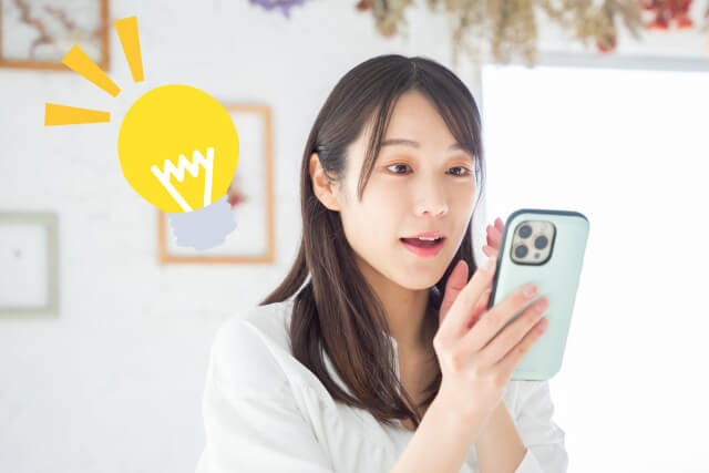 スマホを持ち何かをひらめく女性