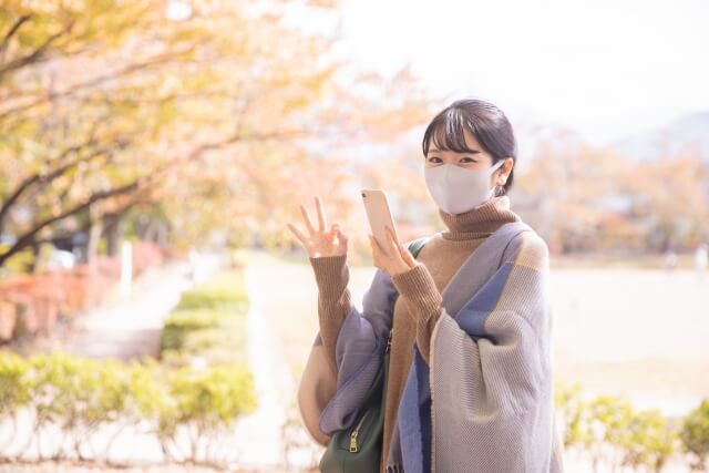 スマホを持ってokサインする女性